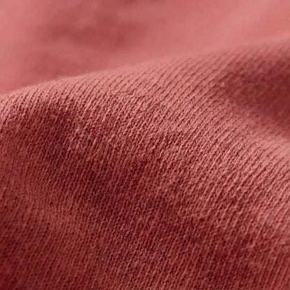 Close-up detail of the 6.4 oz Comfort Colors 1466 garment-dyed natural cotton fabric texture in a deep terracotta tone.