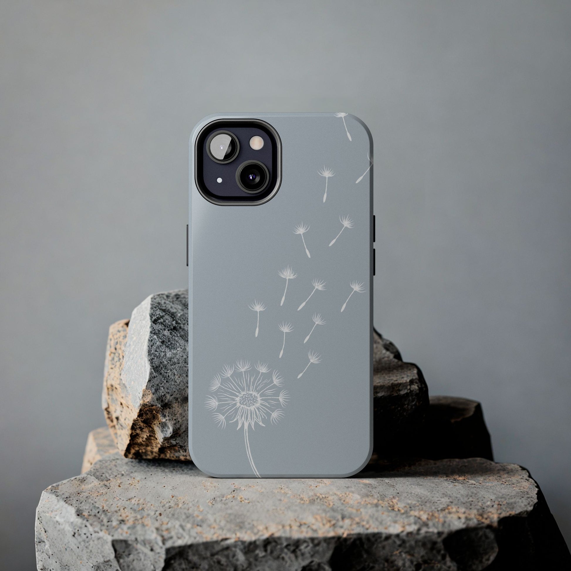 Dandelion Phone Case with a delicate drifting dandelion seed design, shown on a rock for a nature-inspired aesthetic.