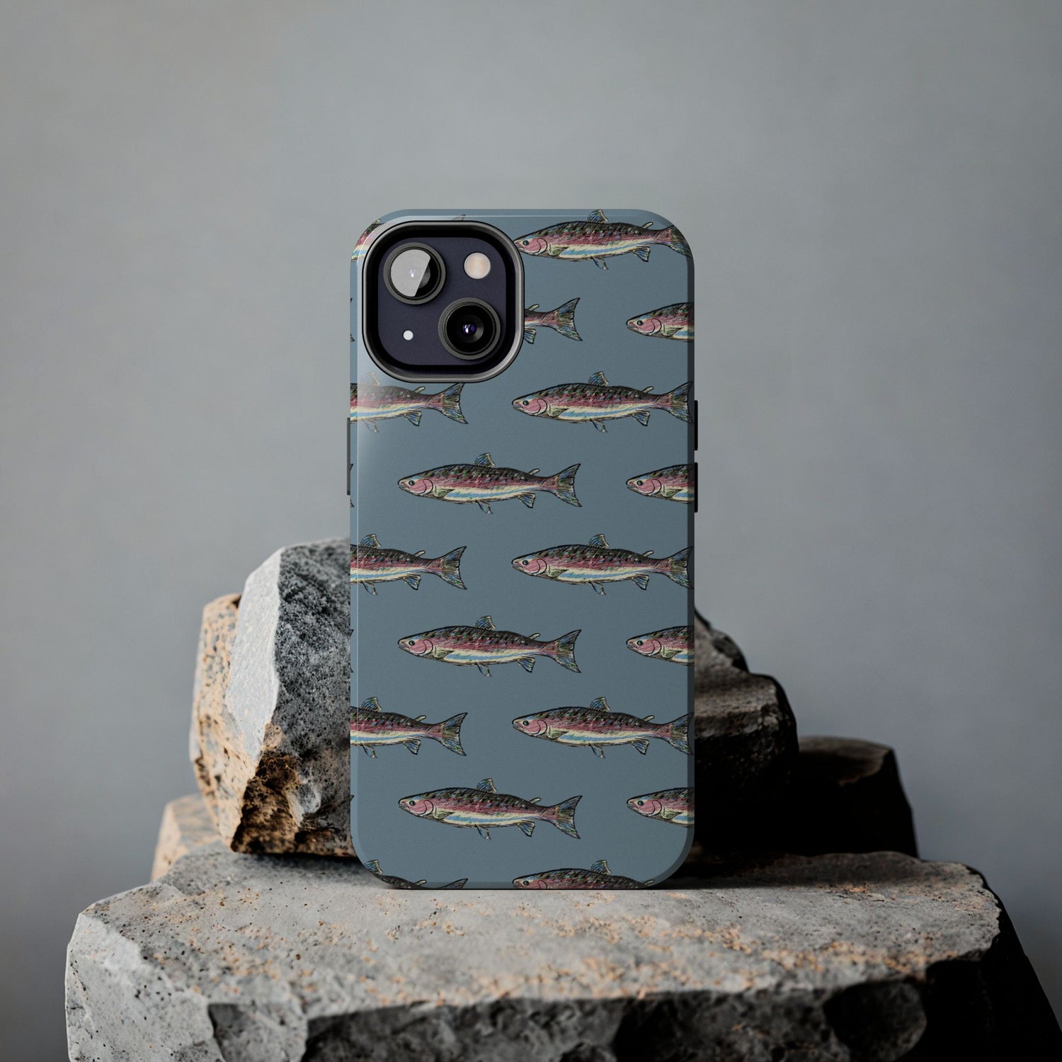Illustrated rainbow trout durable phone case for anglers on a rock lifestyle view.  Compatible with iPhone and Samsung Models. 