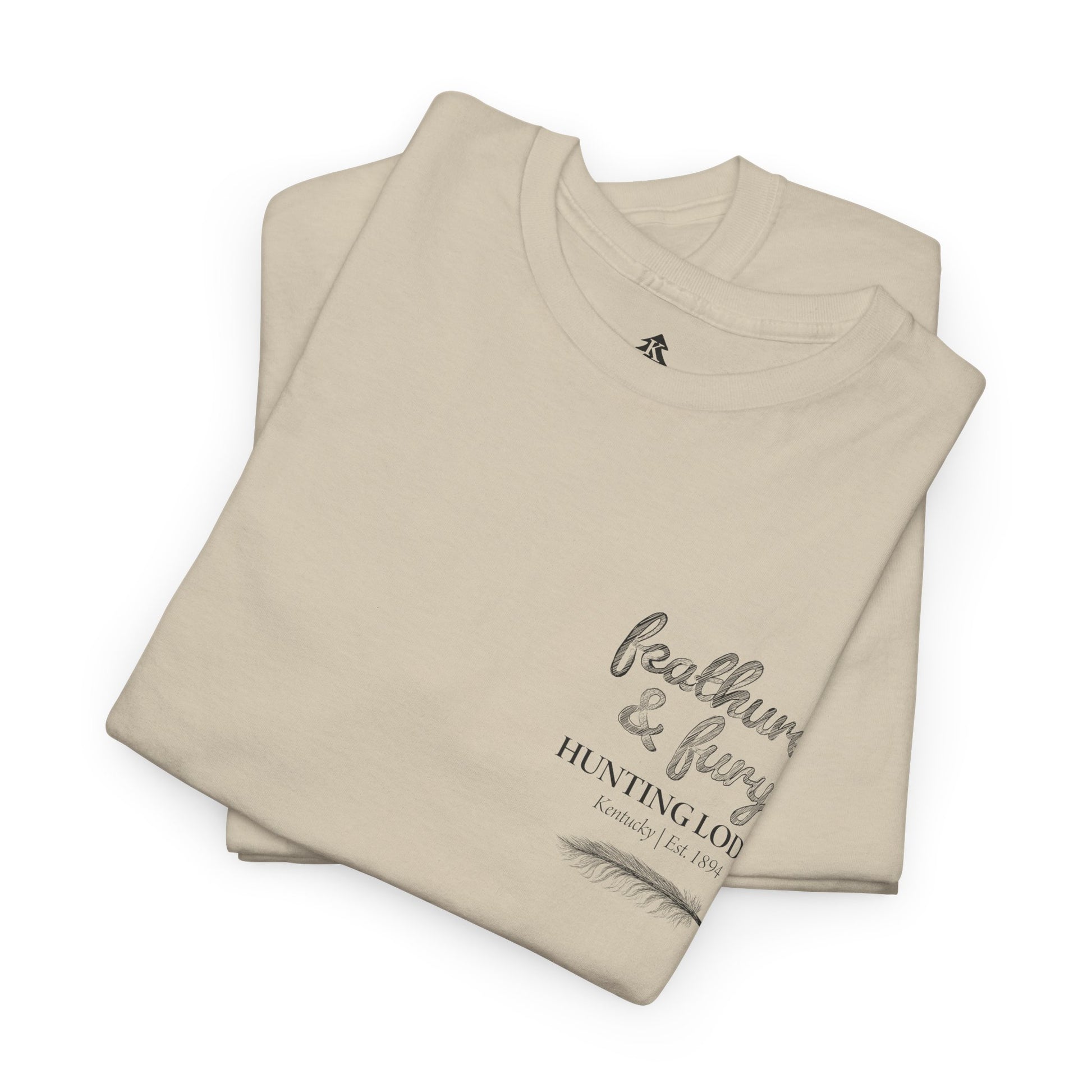 Sand color folded Feathers & Fury Hunting Lodge Tee on a white background, highlighting its comfortable fabric and detailed turkey hunting graphic.
