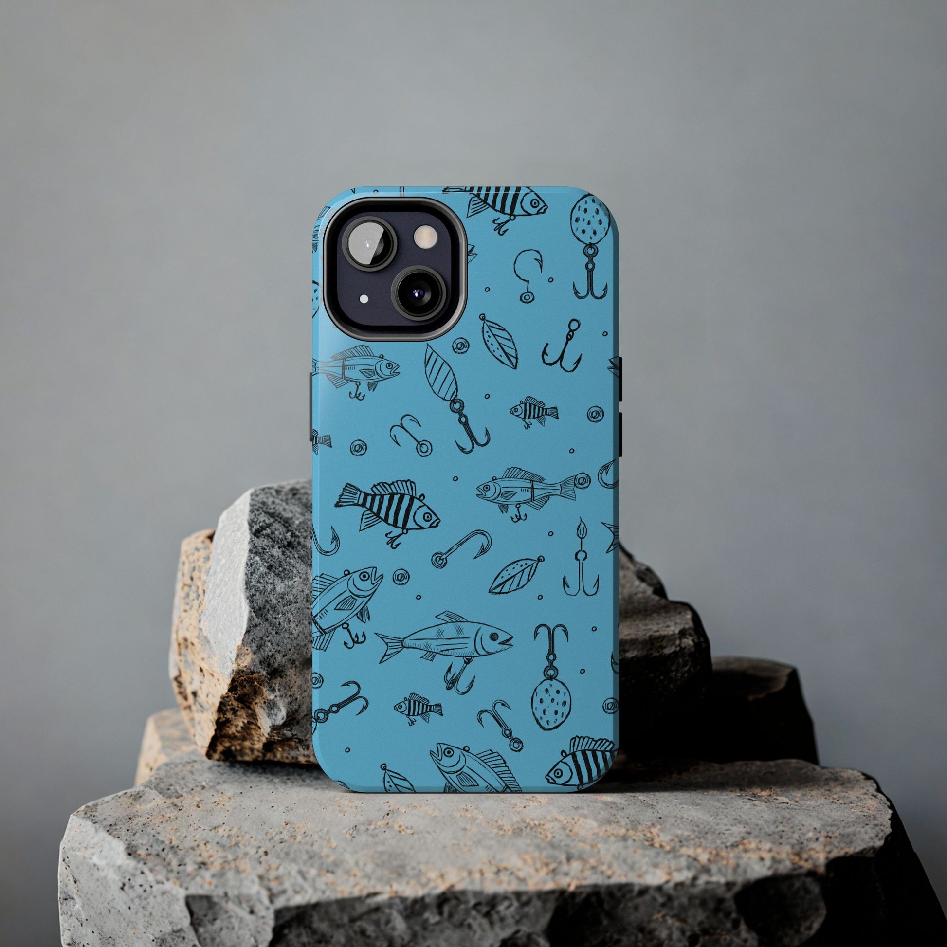 Fish Lure iPhone Case with a detailed fishing lure pattern, shown on a rock for an outdoor-inspired setting.