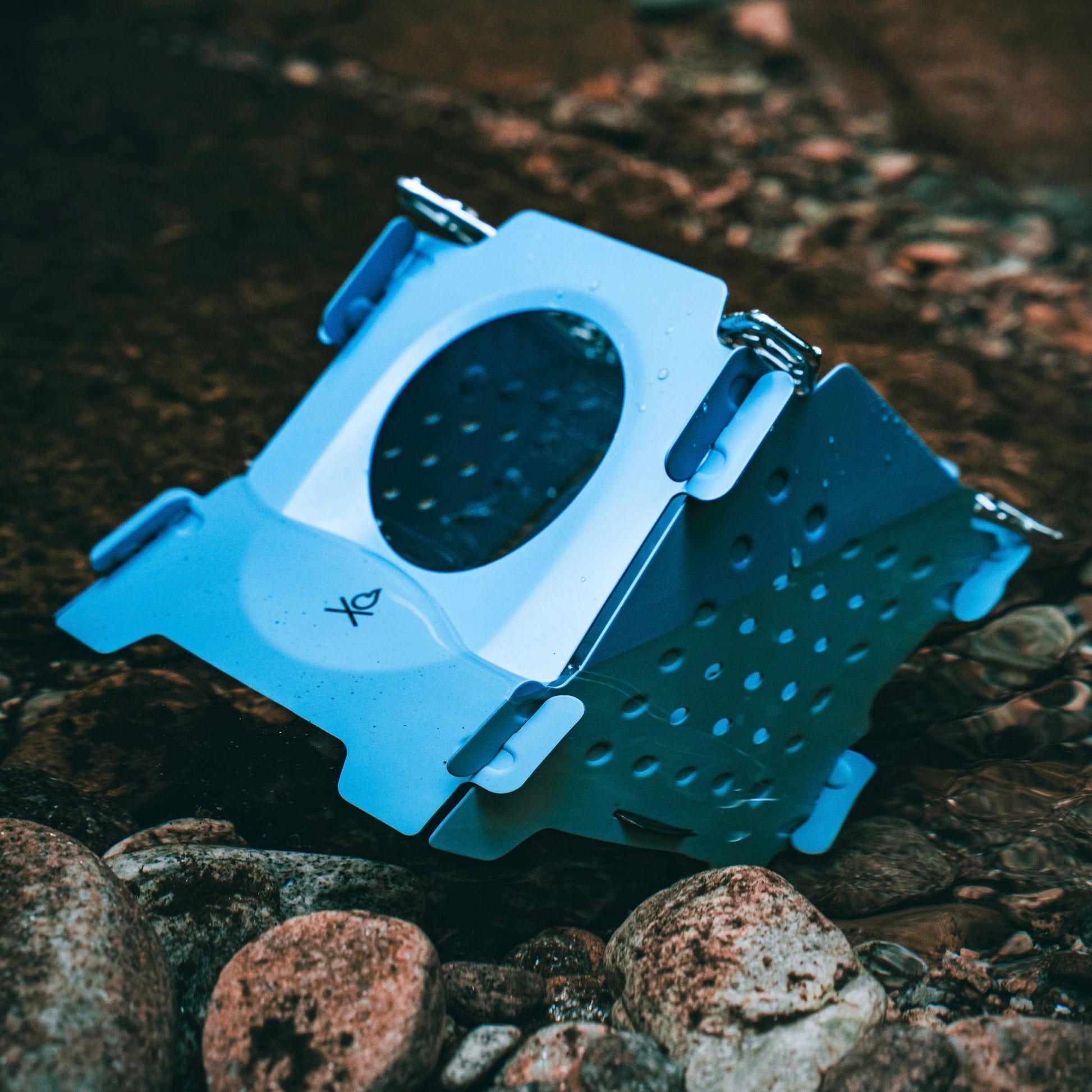 The blue Stöker Stove by Überleben submerged in river.