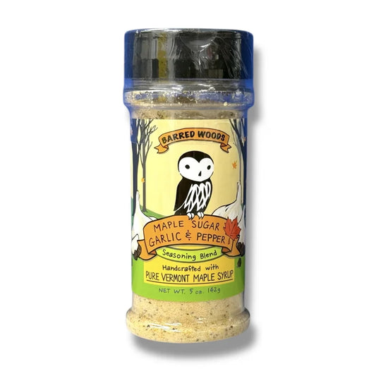 A clear plastic shaker bottle of Barred Woods Maple Sugar, Garlic & Pepper Seasoning Blend, featuring a yellow and green label with an owl illustration and a blue cap, set against a plain white background.