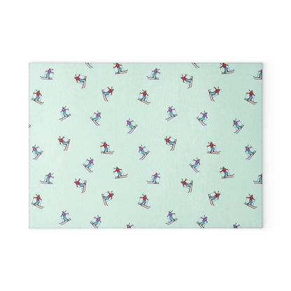 Glass cutting board featuring an illustrated skier pattern, titled 'Carving the Slopes,' displayed on a white background, perfect for winter sports enthusiasts and holiday kitchens.