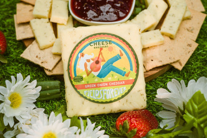 Green Onion Cheddar by Cheese Brothers, Inc. sold by Kempain Family Outfitters displayed in near a cheese board with crackers and jam.