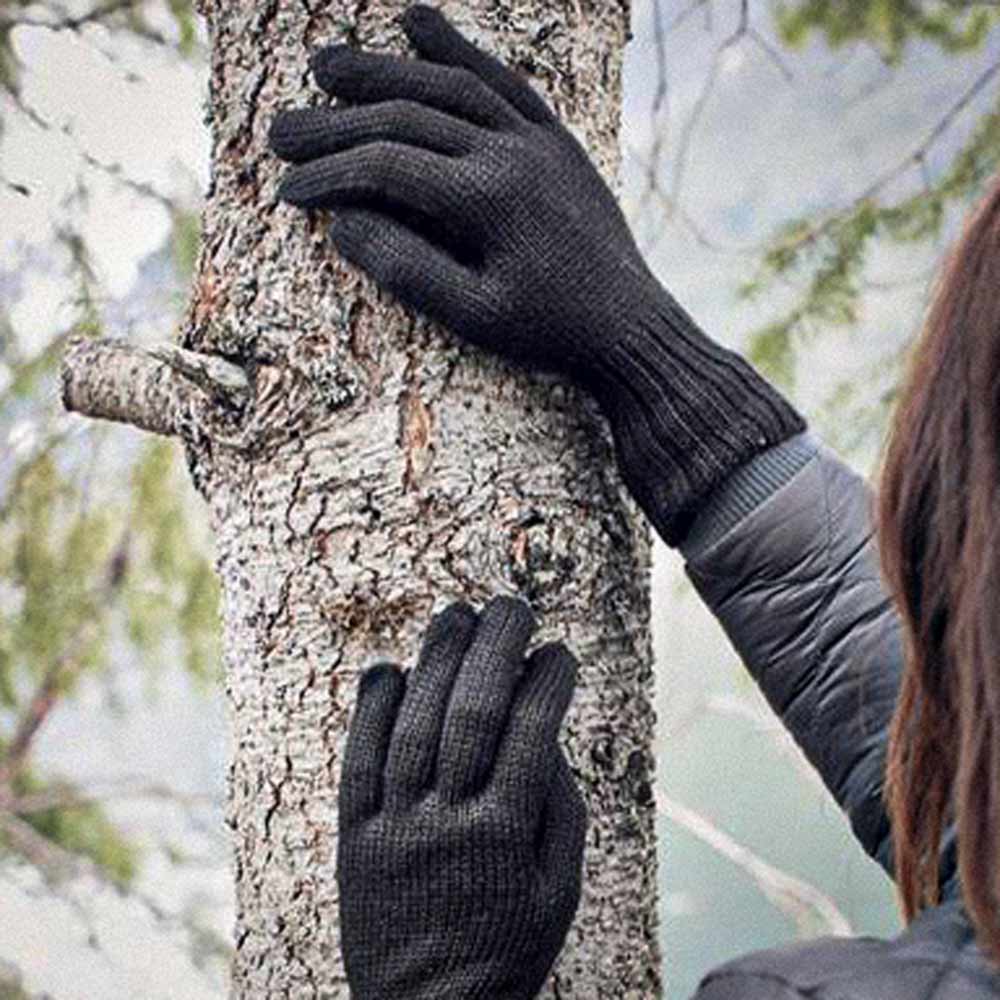 Black knit alpaca gloves worn on a person's hands, shown touching a tree trunk outdoors.