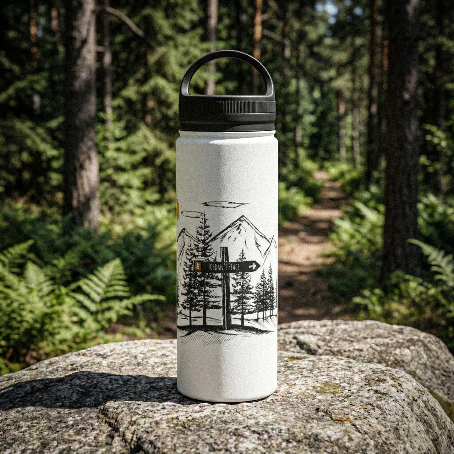 A professional heritage-style photograph of a matte white 18oz stainless steel water bottle with a custom mountain etching sitting on a sun-drenched rock in the woods.