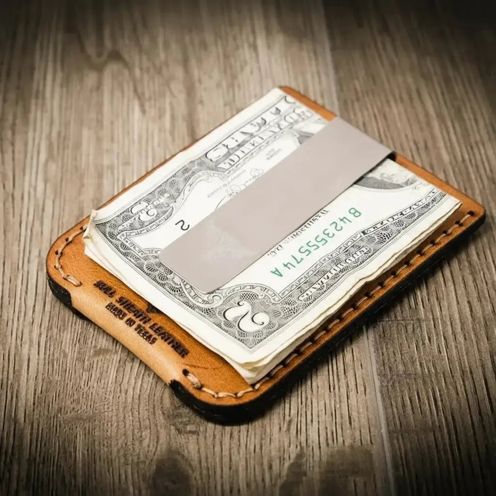 Leather money clip holding a dollar bill on a wooden surface