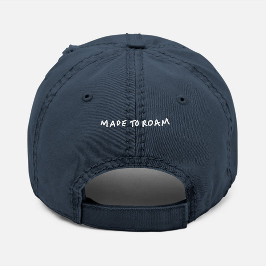 Back view of navy distressed dad hat on white background with “Made to Roam” embroidered in hand-drawn script.