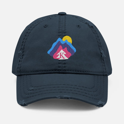  Front view of navy distressed dad hat on white background, featuring an embroidered mountain and sun design with the Kempain Family Outfitters tree + K emblem.