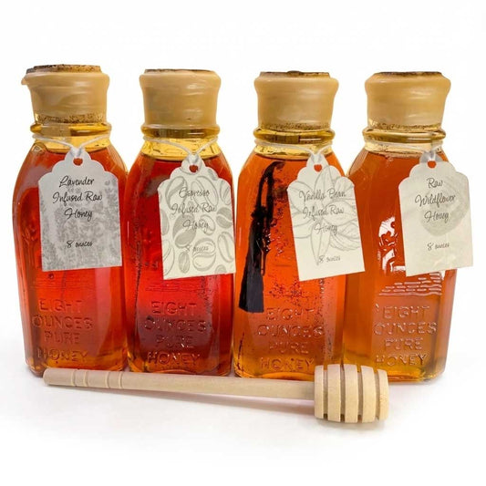 Set of four raw and infused honey jars with cork stoppers and a wooden dipper on a white background. Flavors include Lavender, Espresso, Vanilla Bean, and Raw Wildflower.