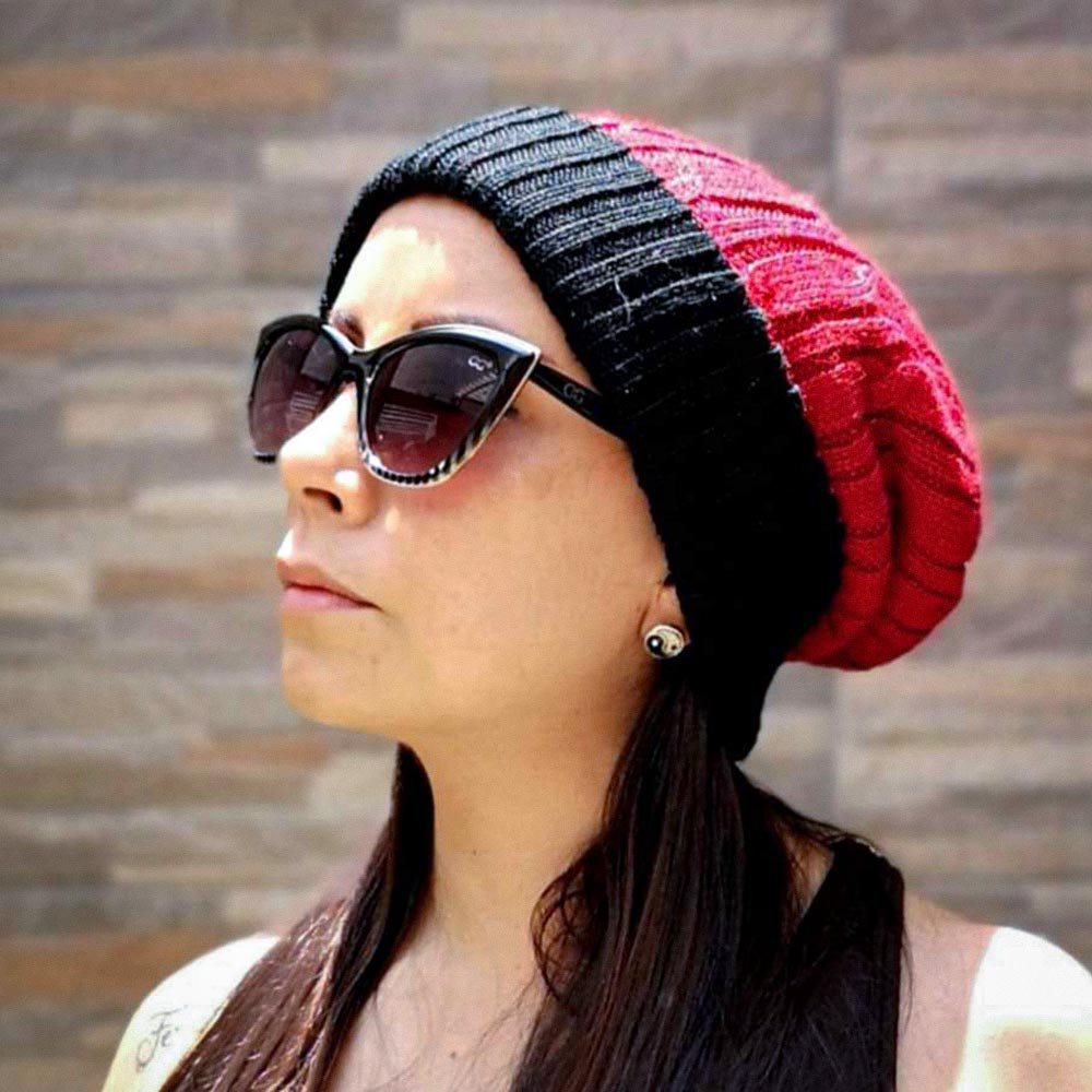 Person wearing a black and red beanie with sunglasses on a neutral background