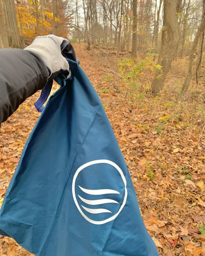 First person point of view of person holding the reusable do it yourself trash cleanup Kit by United By Blue.