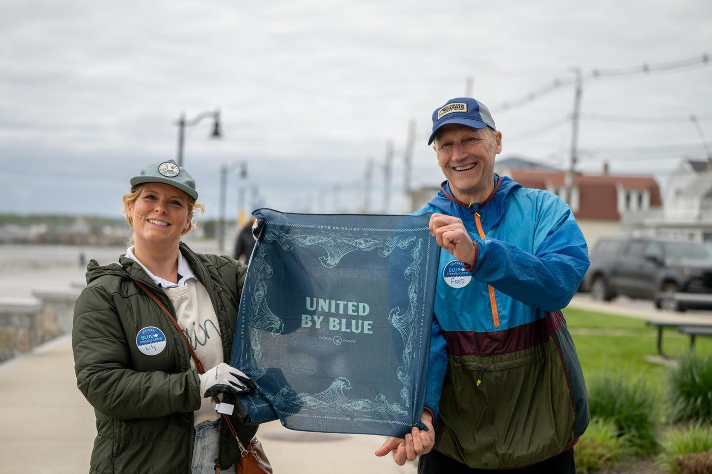 A couple holding up a United By Blue bandana as part of the reusable do it yourself trash cleanup Kit - recycled and organic by United By Blue.