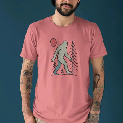 Model wearing the Sasquatch Red Moon Forest Tee with a clean solid background, showing the mystical forest and red moon line art design printed on a coral silk unisex t-shirt.

