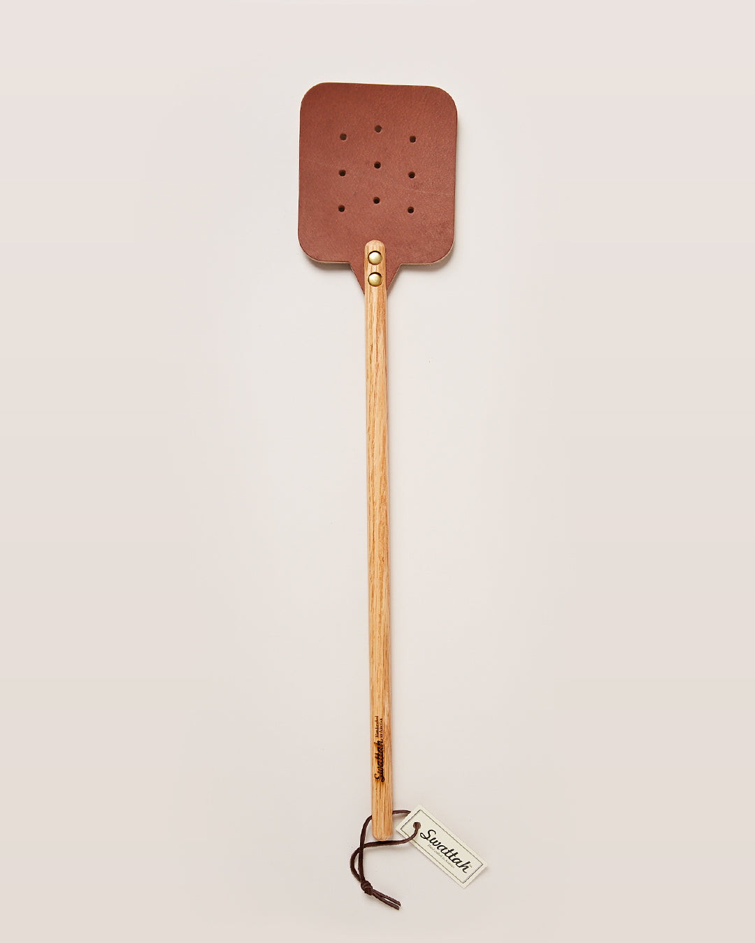 The oak brown Leather Huntsman Flyswatter by Farmhouse Pottery sold by Kempain Family Outfitters displayed on a solid gray background.