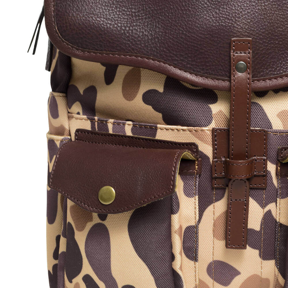 Close up view of The Waxed Canvas Backpack in Smoke-Vintage-Camo by Mission Mercantile Leather Goods showing leather texture and hardware.