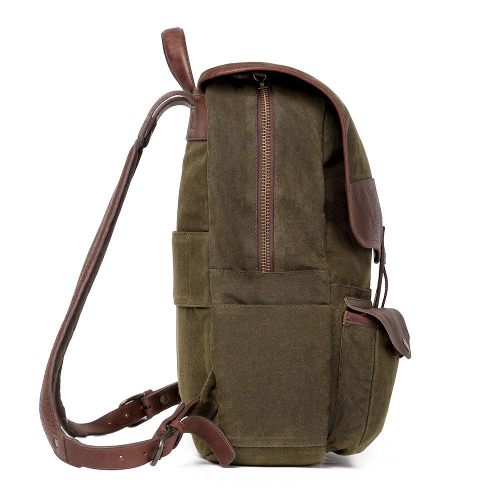 Side profile of The Waxed Canvas Backpack in smoke-forest by Mission Mercantile Leather Goods on a white background.