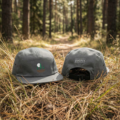 Front and back view of grey low-profile cap with embroidered design of three pine trees, a rising sun, and ripple lines symbolizing the earth on a forest floor.